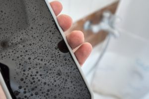 Telefono cellulare utilizzato in bagno con gocce d’acqua sullo schermo