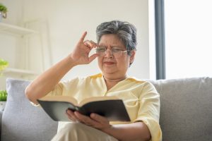 Donna anziana che legge un libro in casa, esempio di attività mentale utile per mantenere la funzione cognitiva con l’età.
