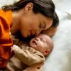 Madre sdraiata vicino al proprio neonato durante un momento di contatto e accudimento, collegato alle trasformazioni del cervello dopo la gravidanza.