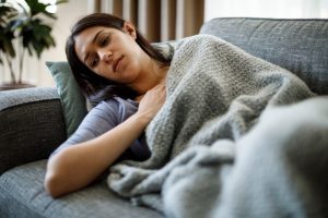 Donna affaticata sdraiata sul divano con coperta, immagine associata alla sindrome da fatica cronica ME/CFS e alla fatigue persistente.