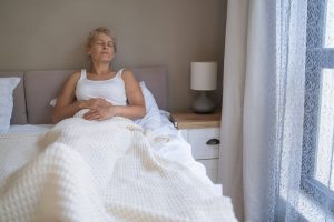 Donna sdraiata a letto durante il giorno, rappresentazione del sonno non ristoratore e della stanchezza tipica della ME/CFS.