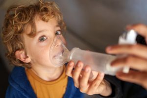 Bambino che utilizza aerosol con maschera per terapia respiratoria, trattamento comune per l’asma e altre malattie delle vie aeree