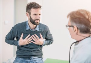 Paziente durante visita medica con sintomi respiratori e dolore toracico, valutazione clinica dell’asma e di disturbi delle vie respiratorie