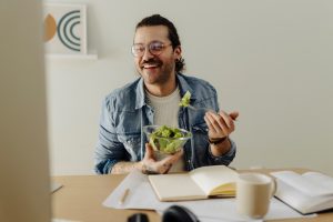 Uomo che consuma un pasto salutare a base di verdure, immagine legata alle corrette abitudini alimentari e al controllo del peso corporeo.