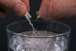 Polvere bianca versata in un bicchiere da due piccole confezioni. L’assunzione di sostanze psicoattive in contesti sessuali può aumentare il rischio di effetti tossici, dipendenza e comportamenti sessuali a rischio.
