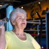 Donna anziana che esegue esercizi di forza con manubri in palestra per contrastare la perdita di massa muscolare e prevenire la sarcopenia.