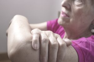Anziana con dolore e debolezza al braccio, possibile segnale di perdita di forza muscolare associata a sarcopenia e invecchiamento.