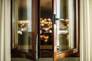 Finestra aperta nelle ore serali con vista sulla città illuminata. Il ricambio d’aria negli ambienti chiusi resta importante anche in estate per limitare l’accumulo di microrganismi e inquinanti indoor.