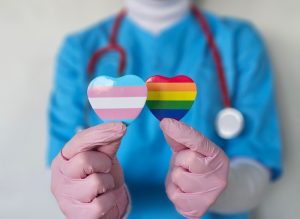 Operatore sanitario mostra simboli delle comunità transgender e LGBTQ+, tema dell’accesso inclusivo alle cure e della salute delle minoranze sessuali e di genere.