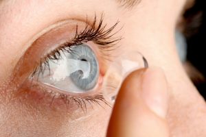 Persona che inserisce una lente a contatto nell'occhio, corretta applicazione delle lenti prima dell'uso.