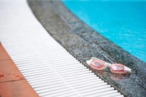 Occhialini da nuoto appoggiati a bordo piscina, alternativa più sicura alle lenti a contatto durante il bagno.