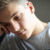Primo piano di un ragazzo con espressione pensierosa e abbattuta, possibile manifestazione di sofferenza psicologica, isolamento emotivo o difficoltà nella gestione delle emozioni durante l’adolescenza.