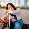 Viaggiatrice addormentata nell’area partenze di un aeroporto, immagine che rappresenta la sonnolenza e l'affaticamento causati dal jet lag dopo lunghi viaggi.