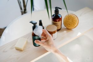 Mano che utilizza un detergente liquido nel bagno con saponi e prodotti per la cura del corpo, rappresentazione dell'igiene intima quotidiana.