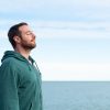 Un uomo che respira l'aria del mare davanti alla costa, convinzione spesso associata ai presunti benefici dello iodio per la tiroide.