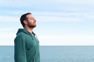 Un uomo che respira l'aria del mare davanti alla costa, convinzione spesso associata ai presunti benefici dello iodio per la tiroide.