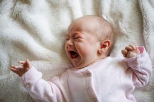 Neonato disteso che piange intensamente durante un episodio di distress infantile nei primi mesi di vita.