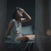 Donna che cerca di rinfrescarsi durante una notte estiva seduta sul letto, esempio di disagio causato dalle elevate temperature notturne.