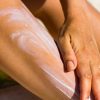 Persona che applica la crema solare sulla gamba prima dell'esposizione al sole per proteggere la pelle dai raggi UV.