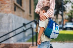 Bambino dall’aria triste accompagnato a scuola.