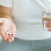 Persona assume compresse con un bicchiere d’acqua durante una terapia
