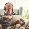 Uomo anziano utilizza un tablet per ascoltare contenuti digitali