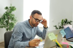 Uomo al computer con in mano fidget toy. Appare concentrato e affaticato durante il lavoro