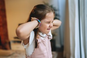 Bambina si copre le orecchie con le mani in un momento di disagio