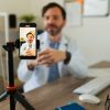 Medico registra un video con lo smartphone durante una sessione di comunicazione sanitaria online.