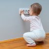 Bambino piccolo tocca una presa elettrica a muro, esempio di rischio domestico da prevenire con apposite protezioni.