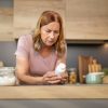 Donna esamina un flacone di integratore alimentare in cucina