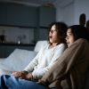 due ragazze spaventate sedute sul divano mentre guardano presumibilmente un film horror