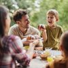 Adulti e bambini felici che condividono il pasto all'aperto