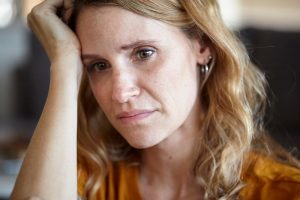 Una donna che appoggia la testa sulla mano con aria pensierosa e preoccupata