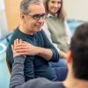 Un uomo stringe la spalla di un altro mostrando supporto in un contesto di supporto psicologico
