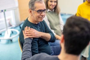 Un uomo stringe la spalla di un altro mostrando supporto in un contesto di supporto psicologico